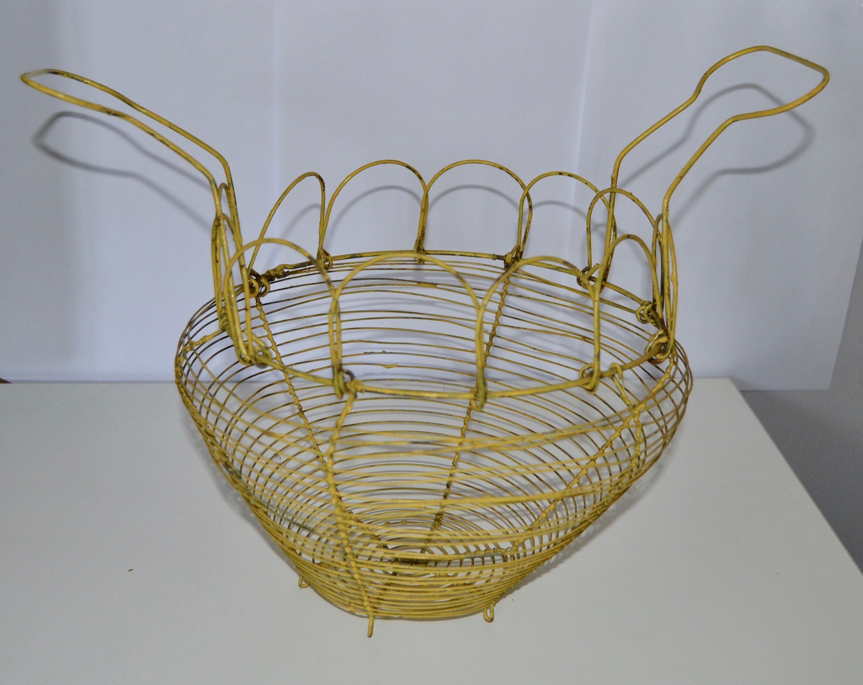 Old egg basket in yellow metal wire