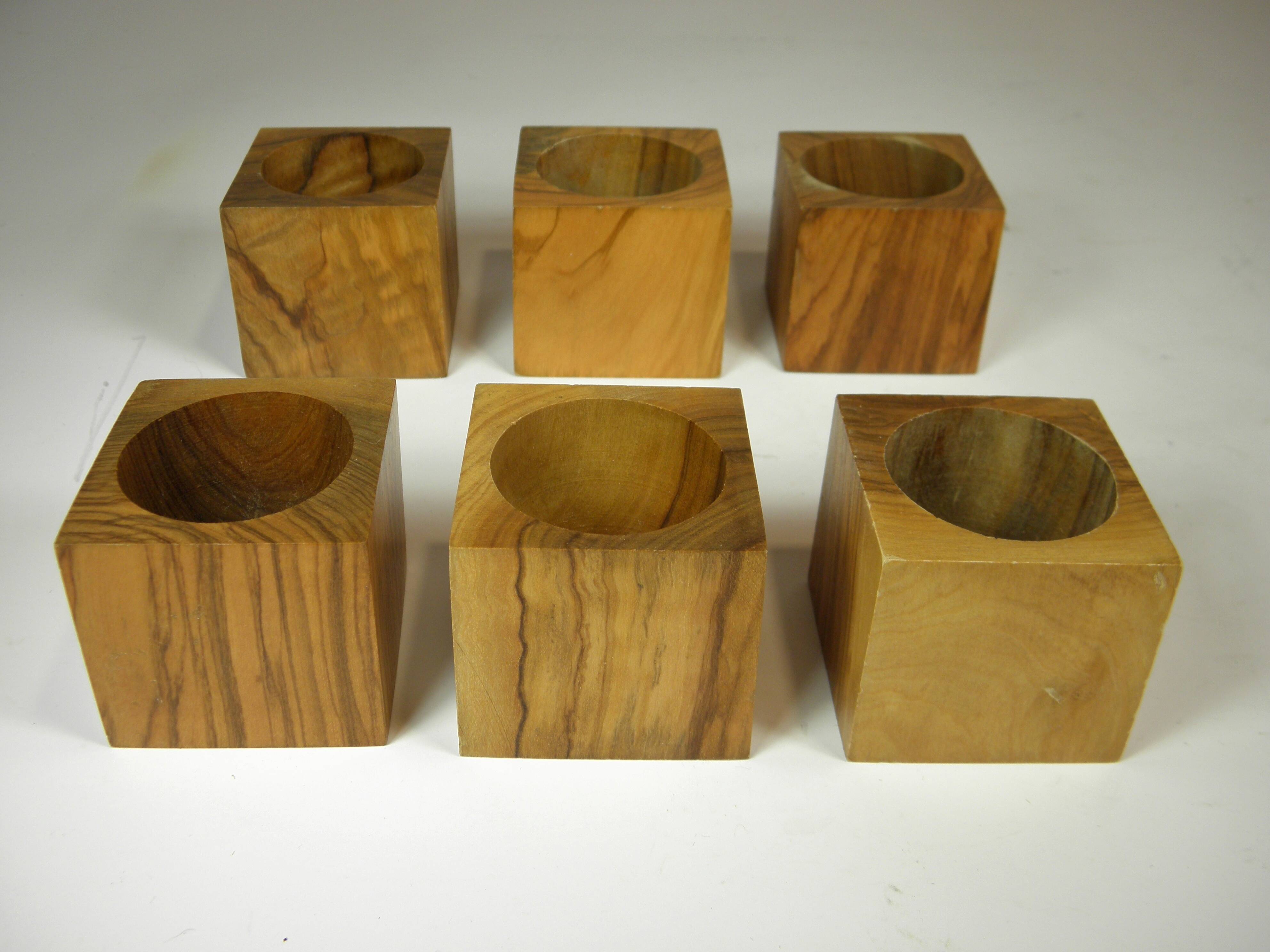 Six egg cups on a wooden tray.