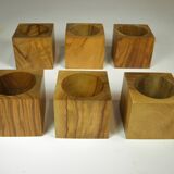 Six egg cups on a wooden tray.