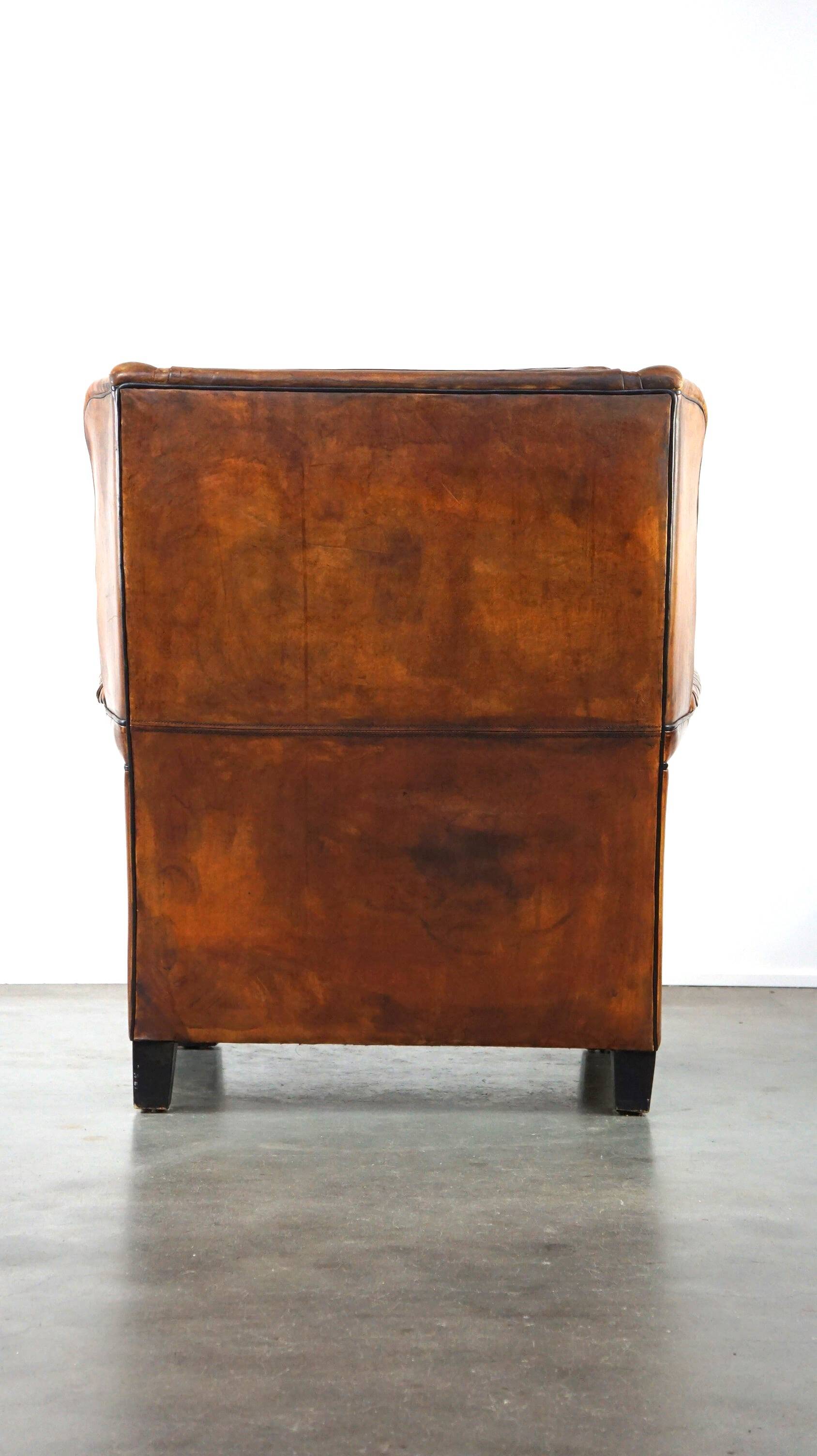 Very large worn sheepskin wing chair with a checked seat cushion