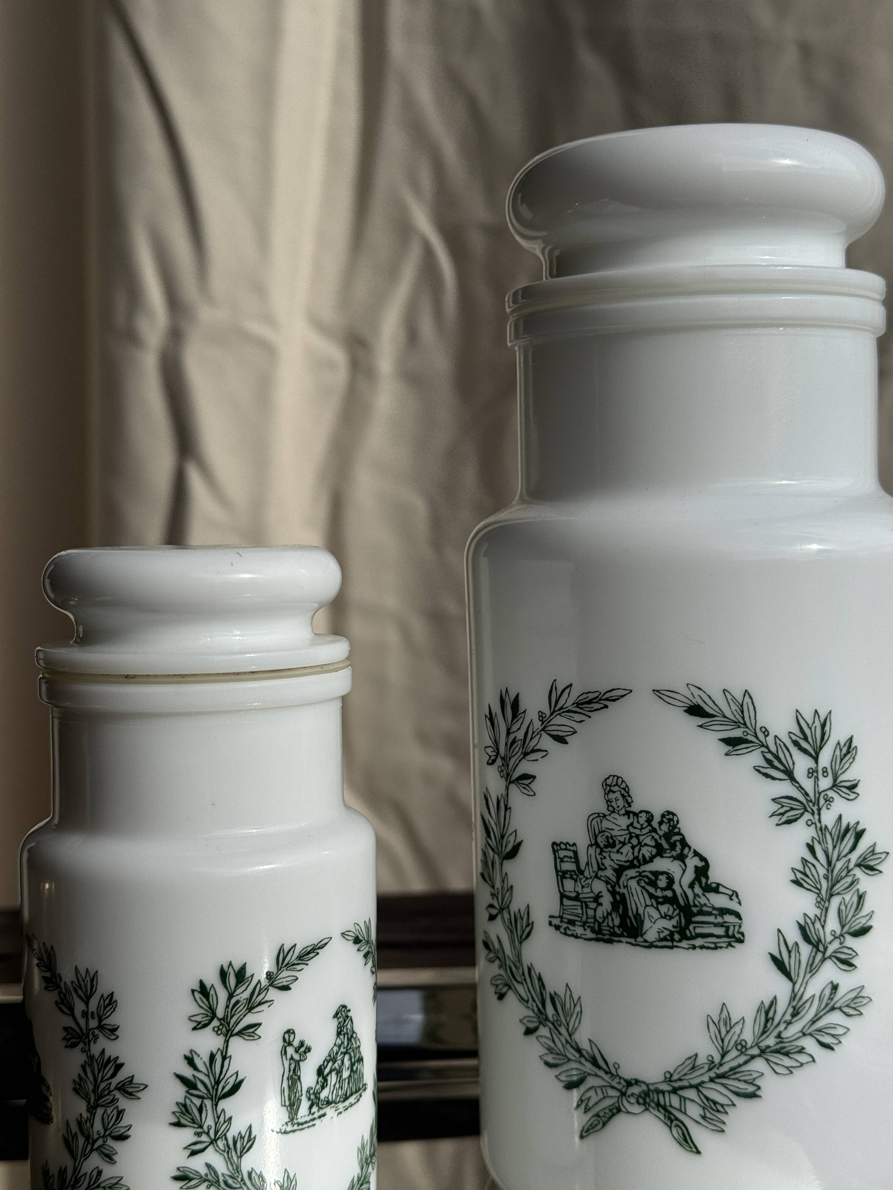 A pair of white glass bottles with Italian green patterns.