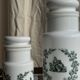 A pair of white glass bottles with Italian green patterns.