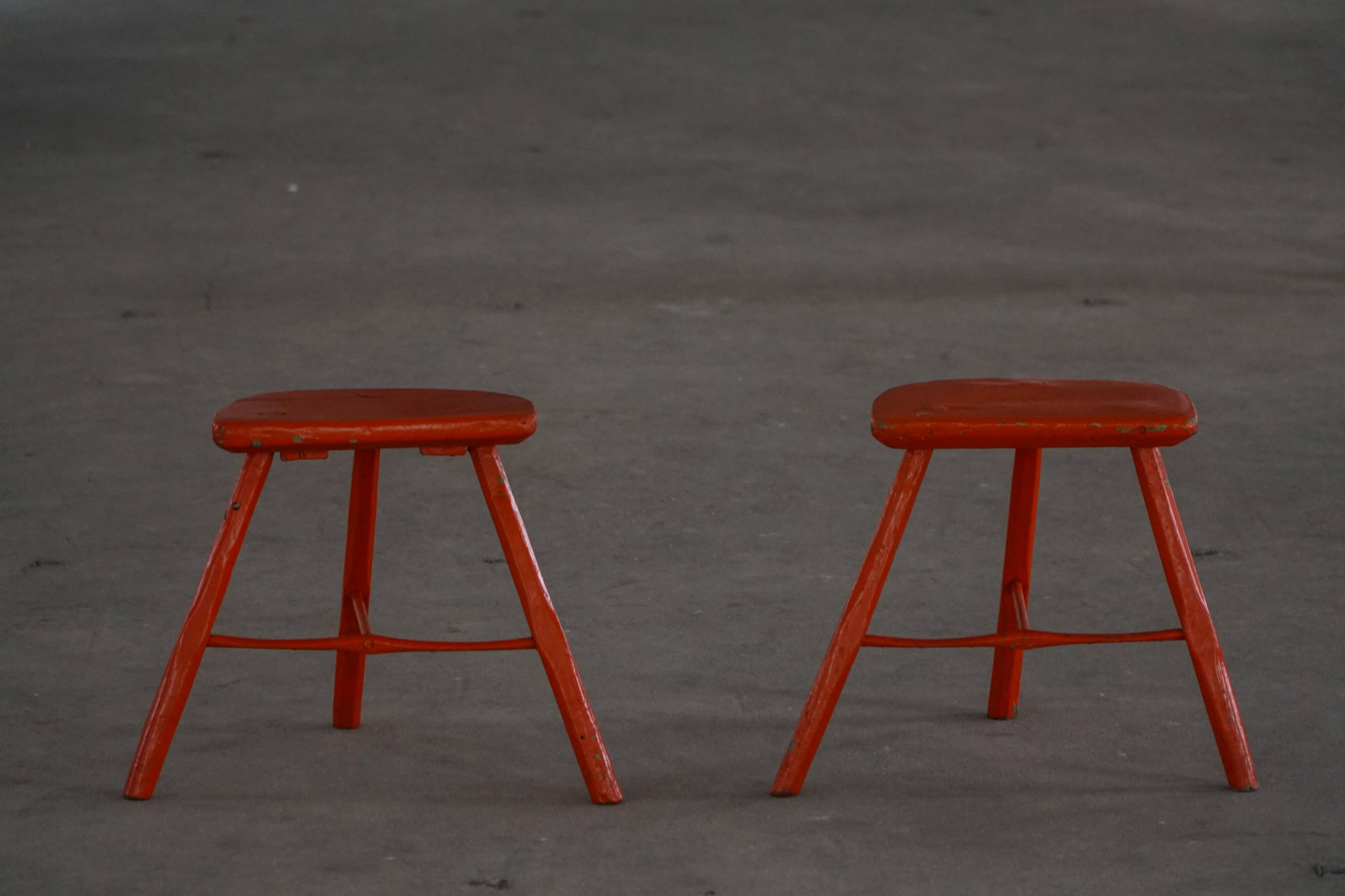 Pair of wooden stools painted in patinated red with flared legs, 1950s-1960s.