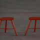 Pair of wooden stools painted in patinated red with flared legs, 1950s-1960s.