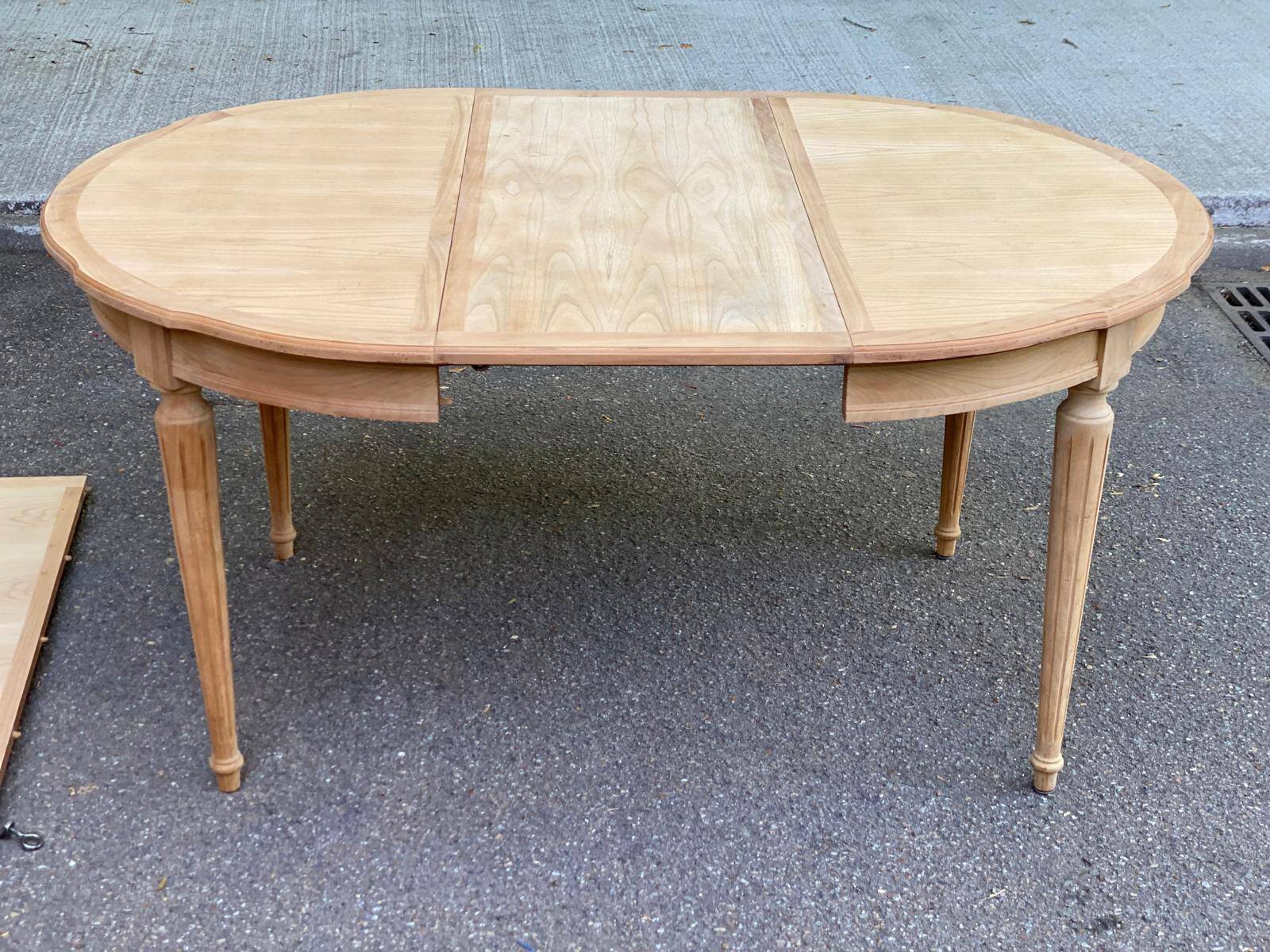 Extendable round table in renovated Louis XVI style, made of light wood, with 2 extensions.