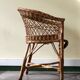 Woven rattan armchair with armrests.