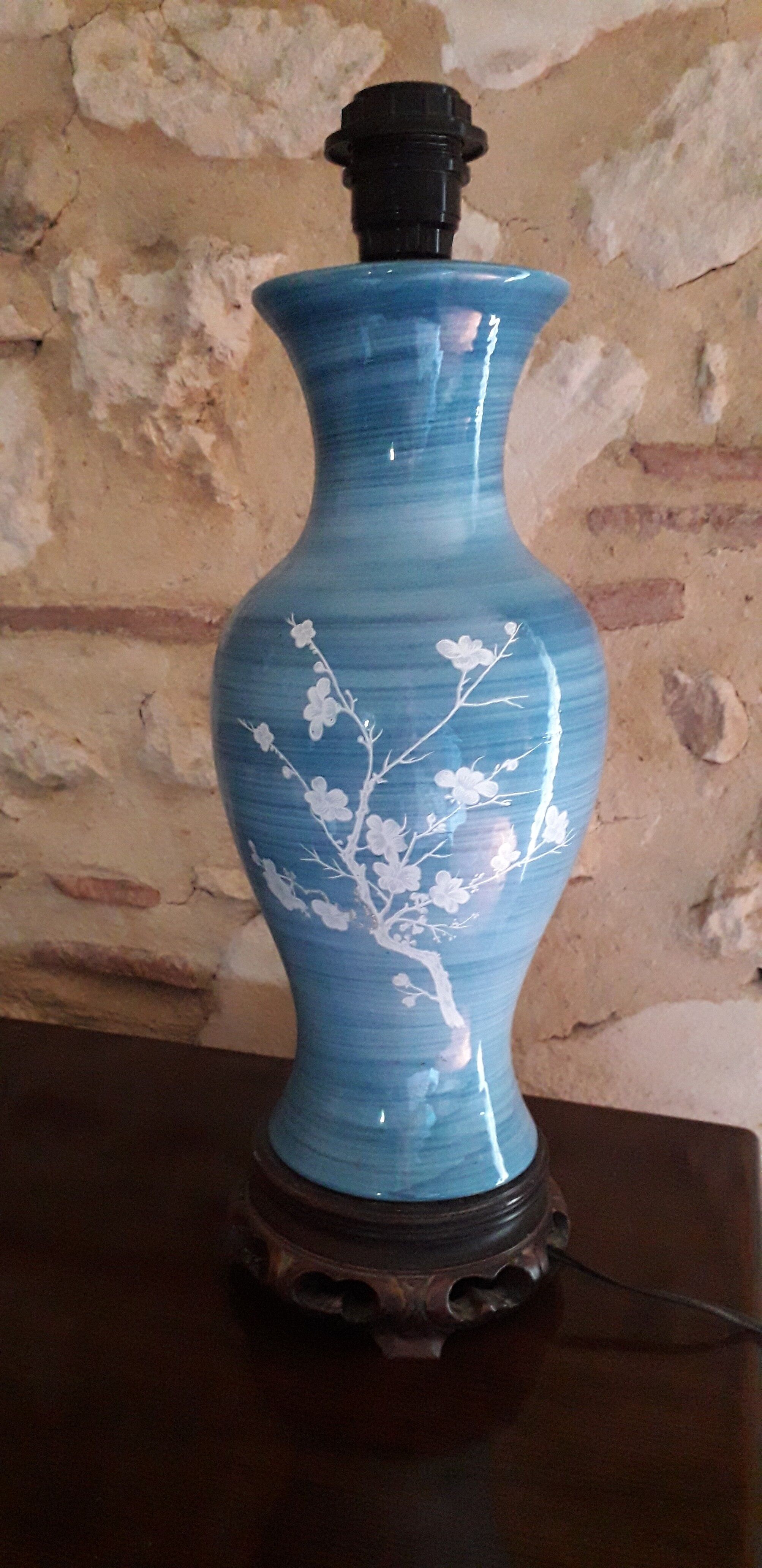 Large blue porcelain lamp with white flowers (cherry blossoms) on wooden stand.