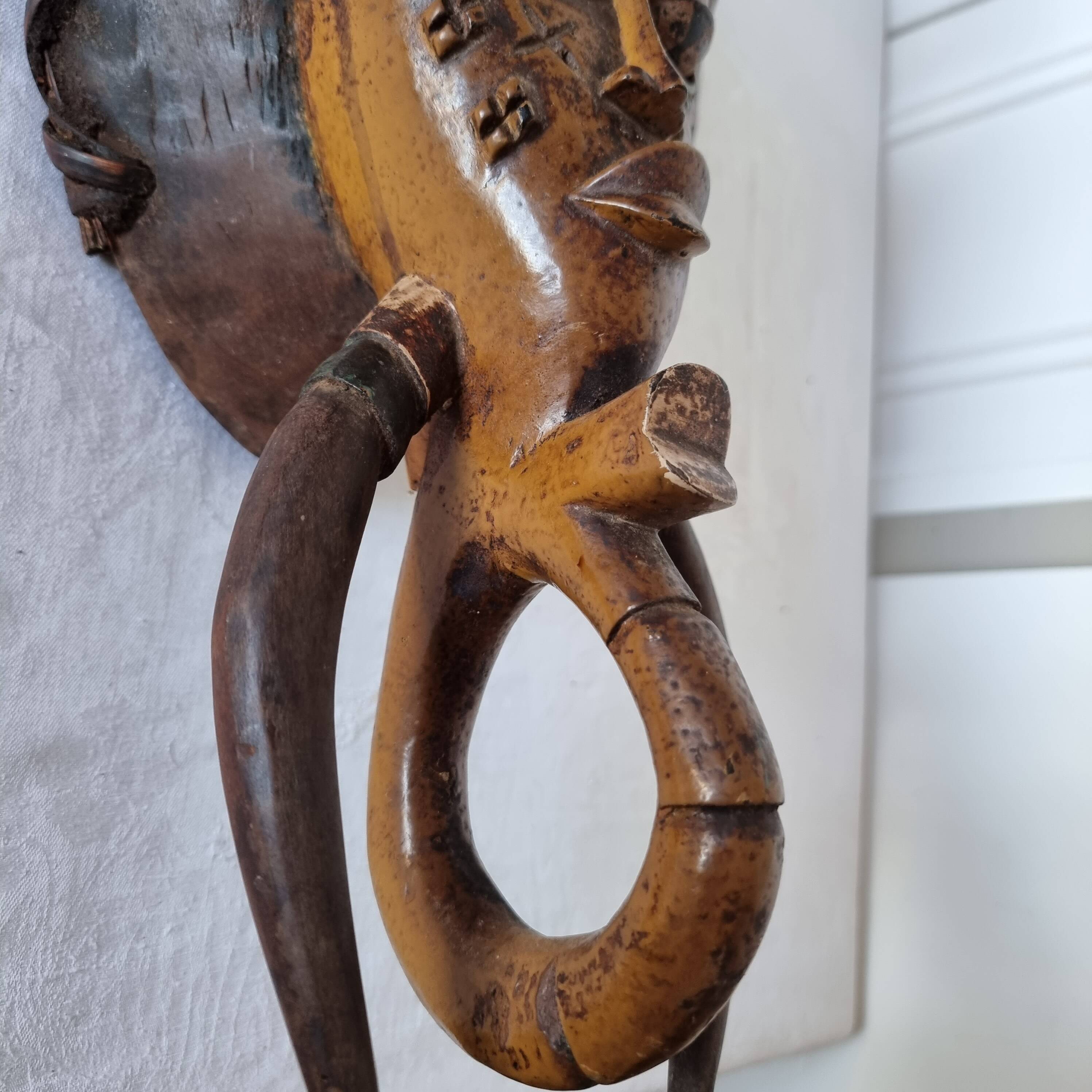 A large Senufo mask made of colored wood, decorated with an anthropomorphic figure