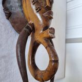 A large Senufo mask made of colored wood, decorated with an anthropomorphic figure