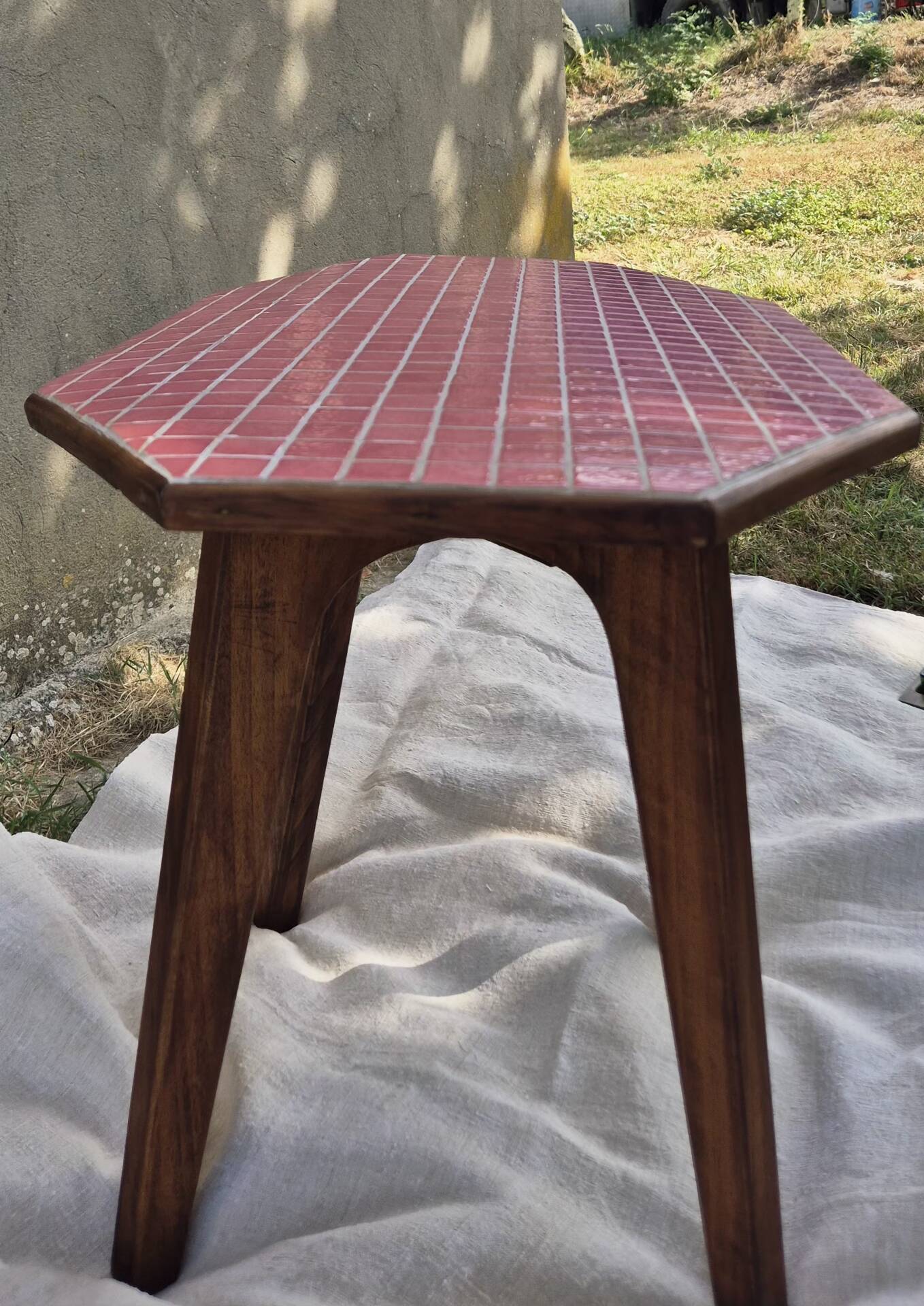 Small Scandinavian side table with wood and pink tiles, with tapered legs.