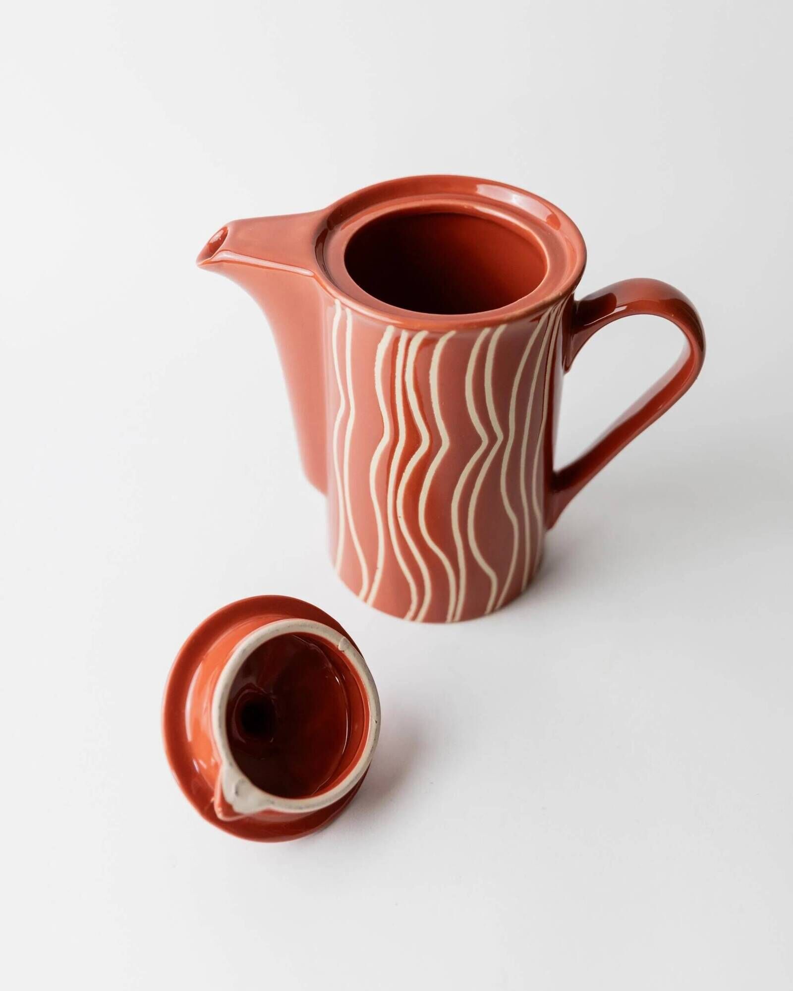 Vintage tea or coffee service in 1970s ceramic, teapot with lid and milk jug, rust orange with retro striped pattern, mid-century decoration, gift idea.