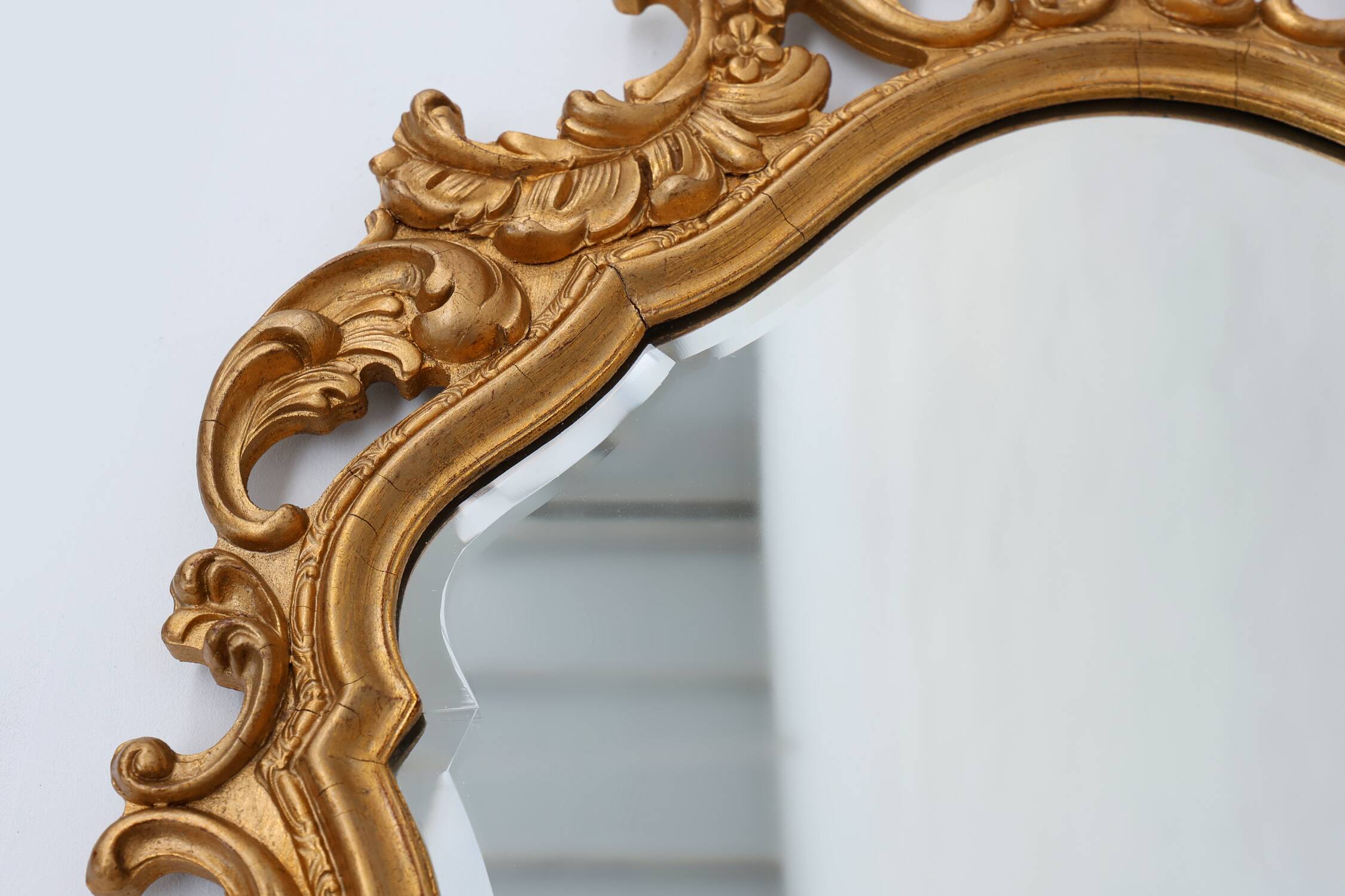 French Rococo or Baroque style facet-cut crest mirror in gilded carved wood