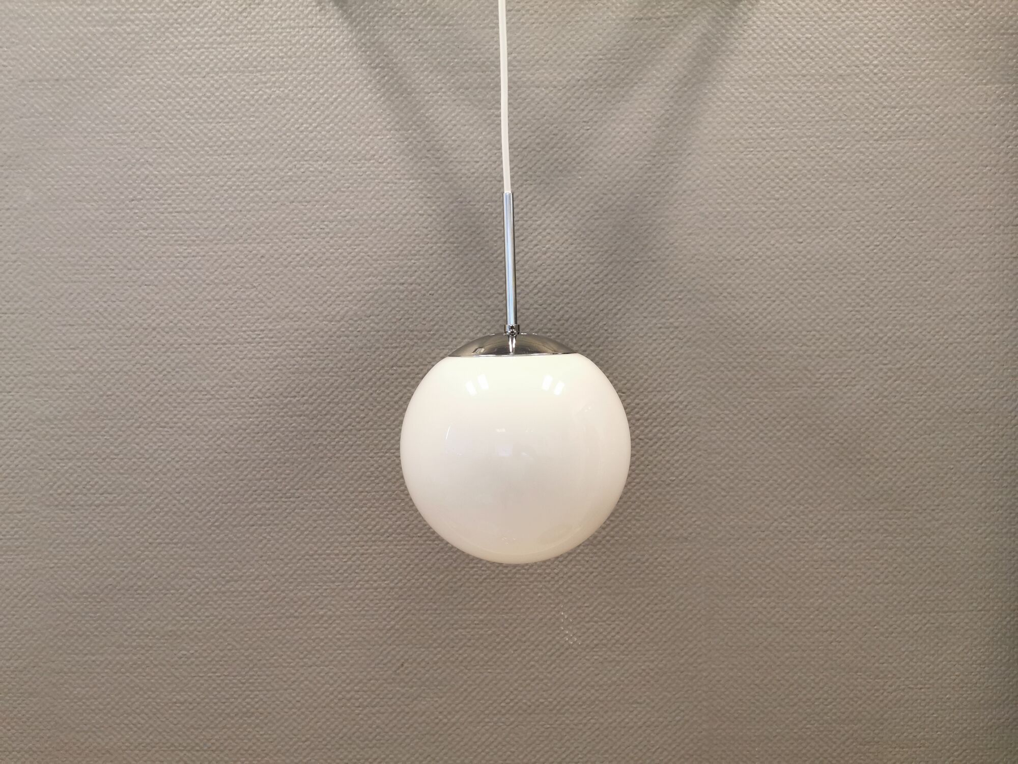 White hanging lamp with metal suspension, made with ball round opal glass shade.