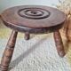 Small brutalist tripod stool made of turned wood.