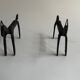 Pair of animal-shaped wrought iron and hammered fire dogs in primitive brutalist style.