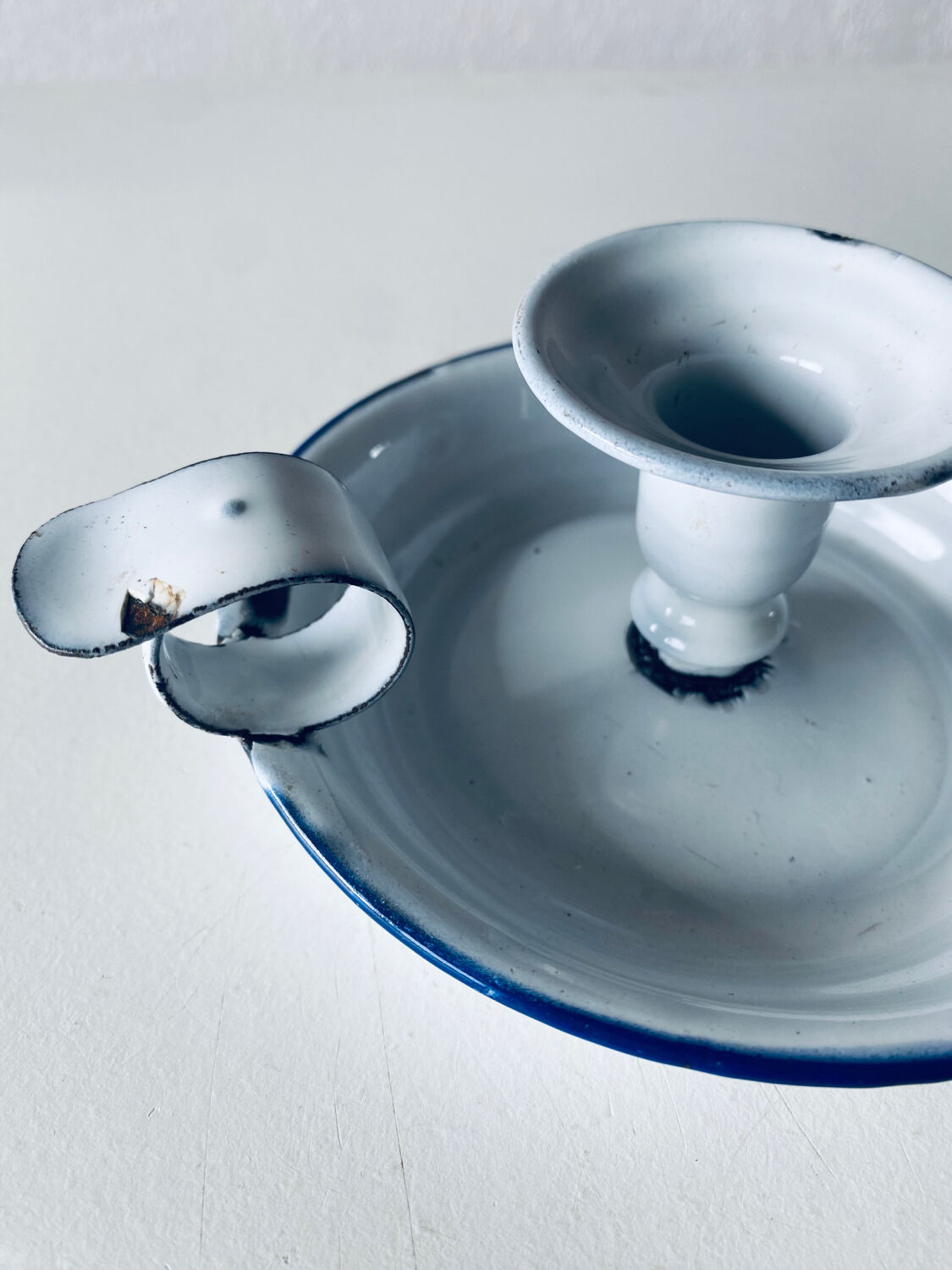 Old candle holder in white enameled metal