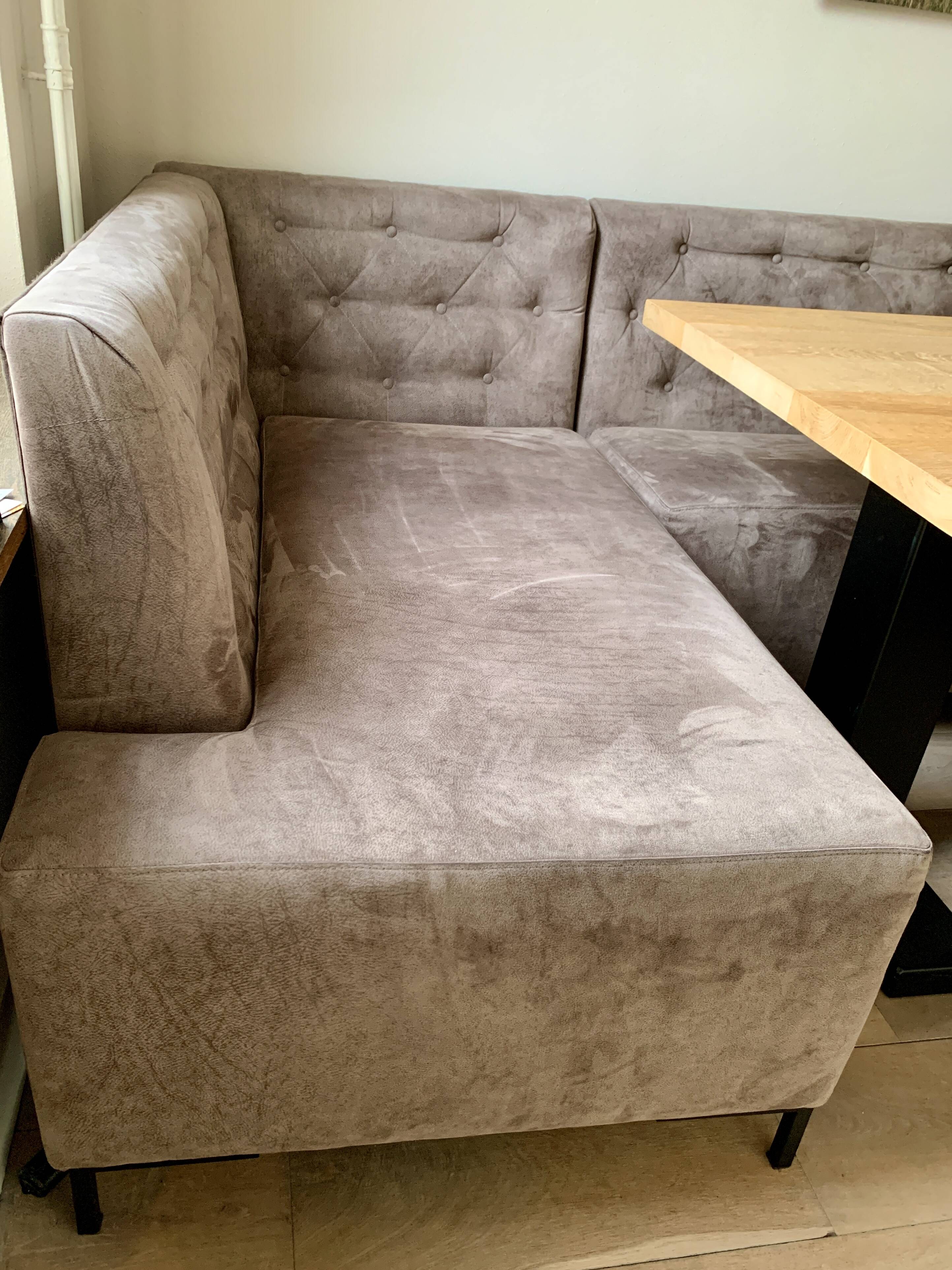 Dining table made of wood with three leather seats and a long leather sofa.