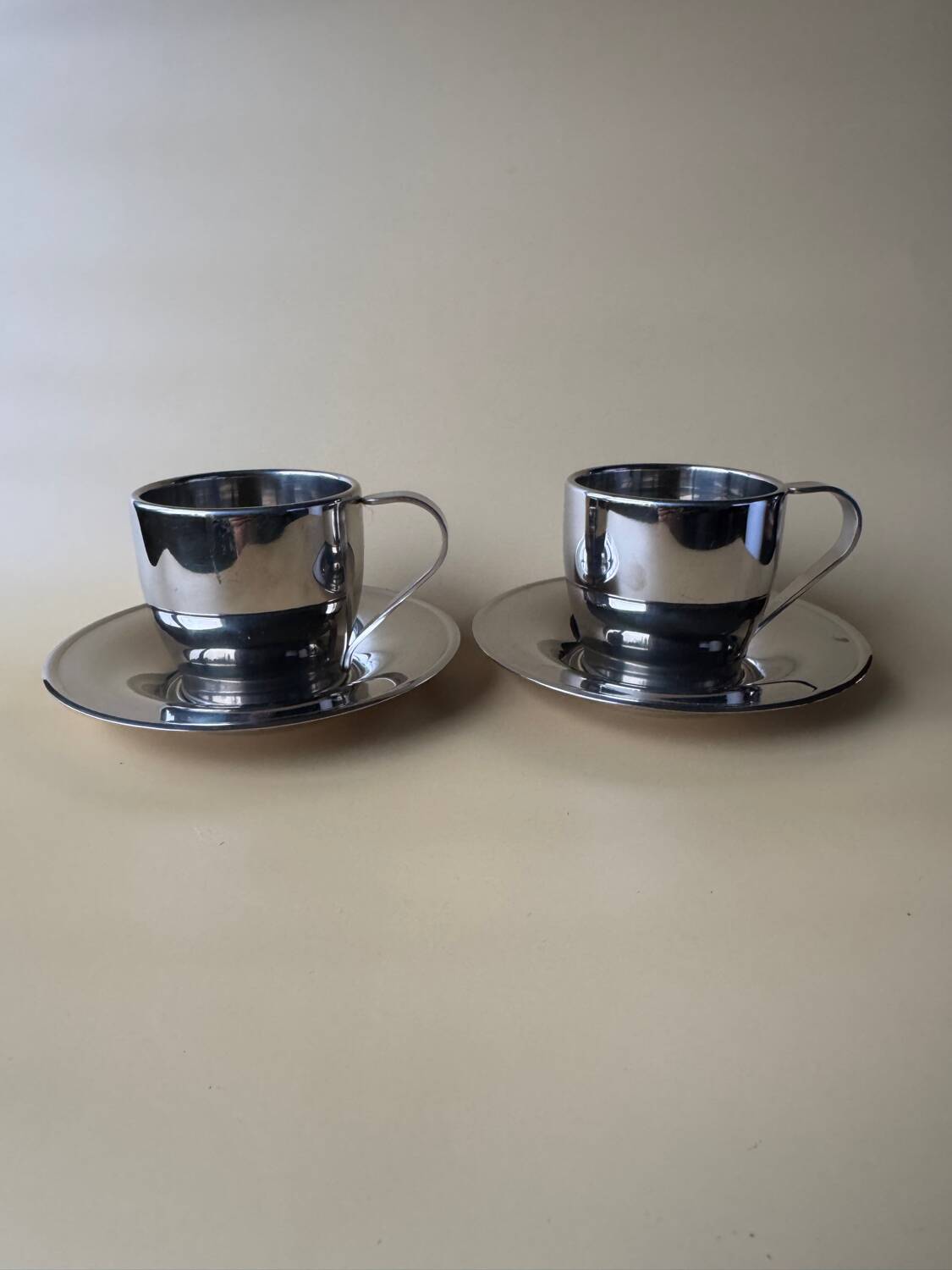 Two vintage mid century modern stainless steel coffee cups with saucer