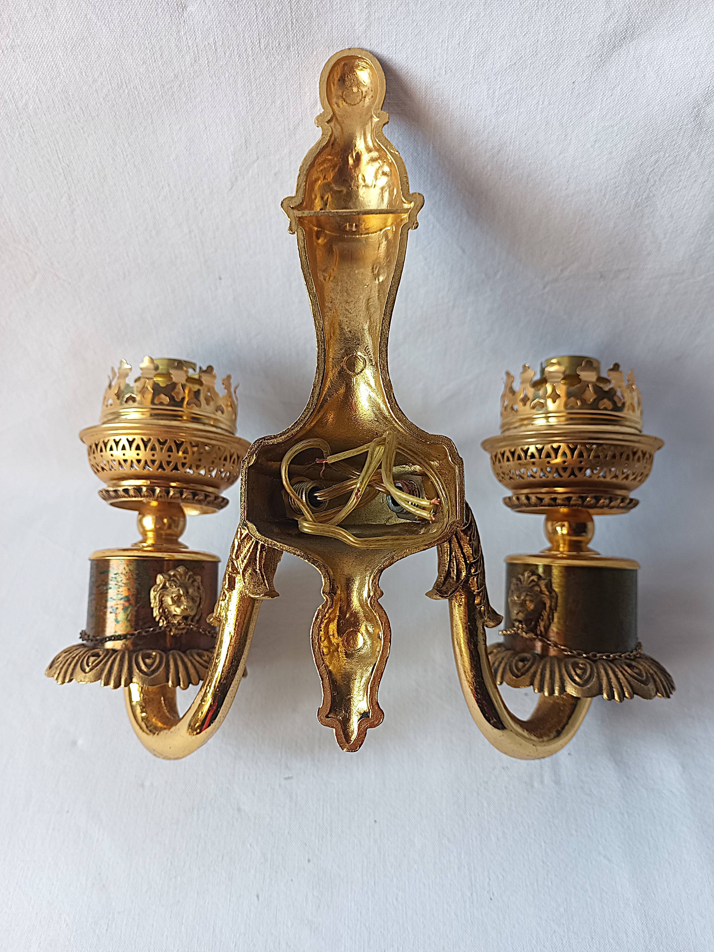 Wall lamp in gilded bronze with a lion's head and engraved globe.