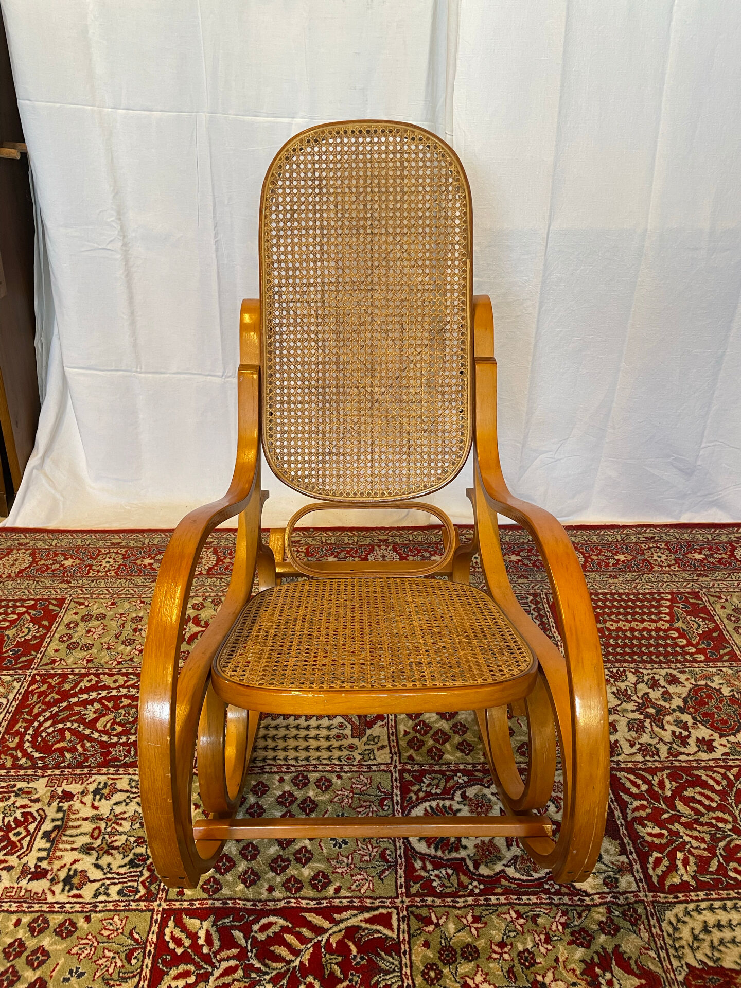 Antique rocking chair in curved wood and caning.