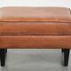 Handy sheepskin ottoman with warm colours finished with black piping