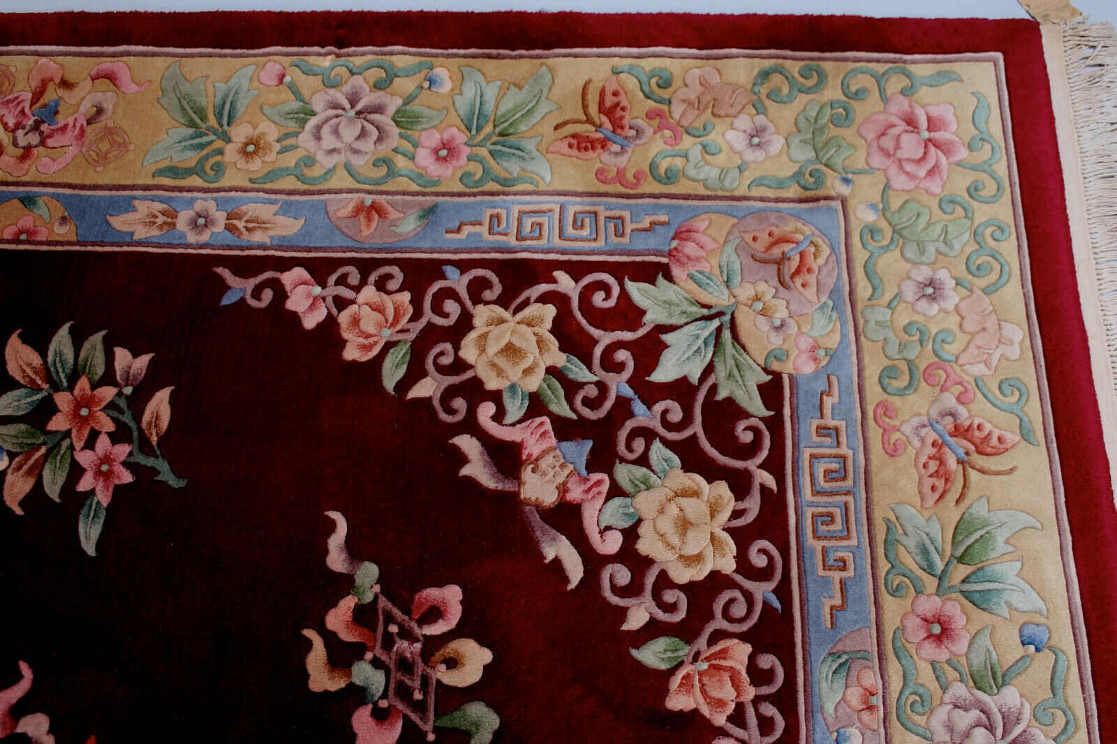 China wool fringed rug with floral pattern on deep plum background 393x274cm