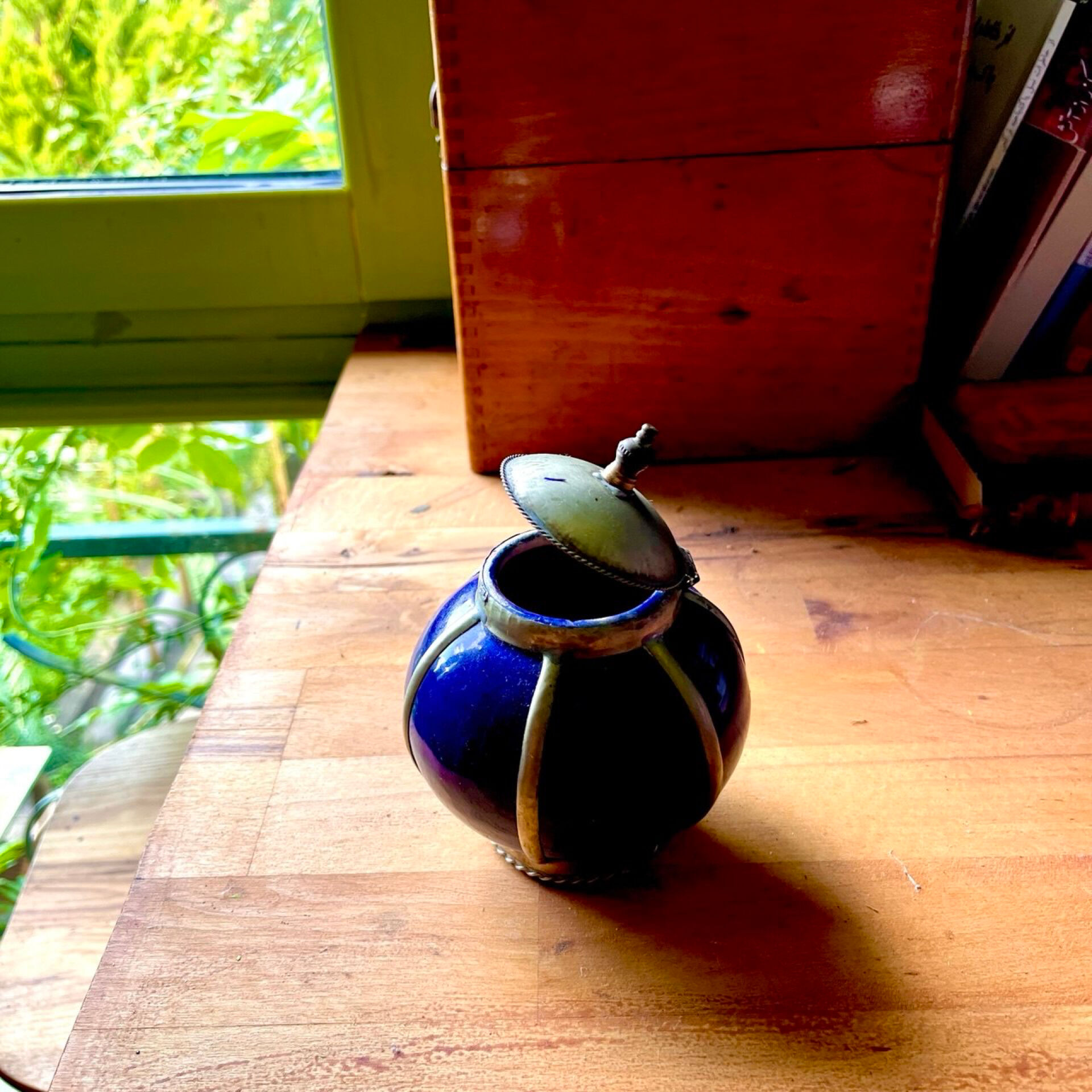 Small blue ceramic pot with metal frame and lid.