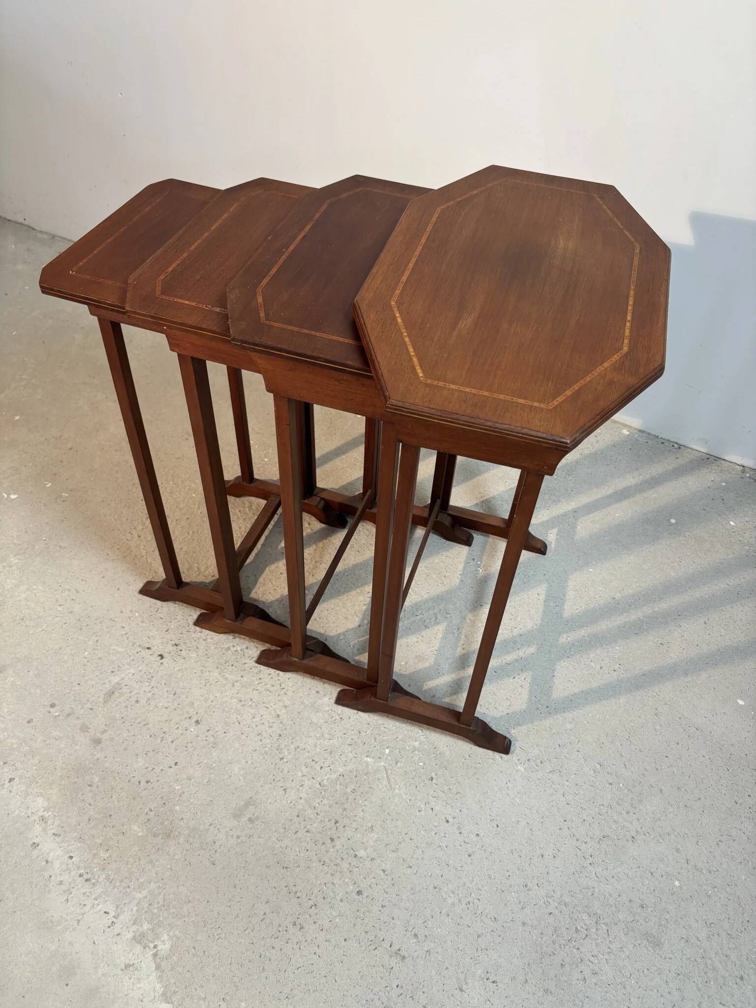 Four nesting tables with polygonal tops and decorative inlays.