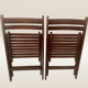 Pair of folding chairs made of dark wood slats.