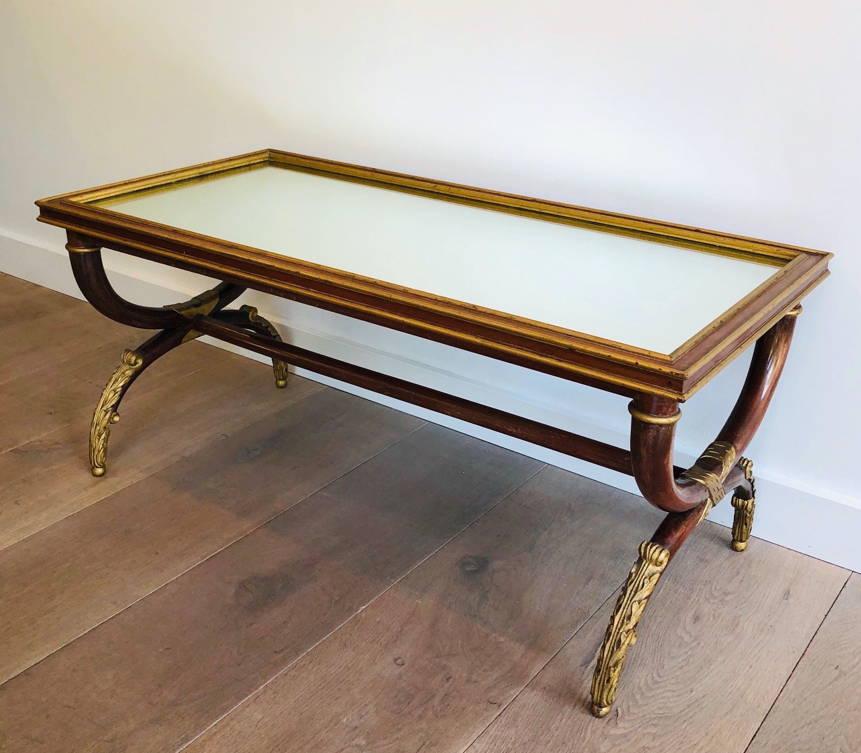 Coffee table in patinated and gilded carved wood with mirror top