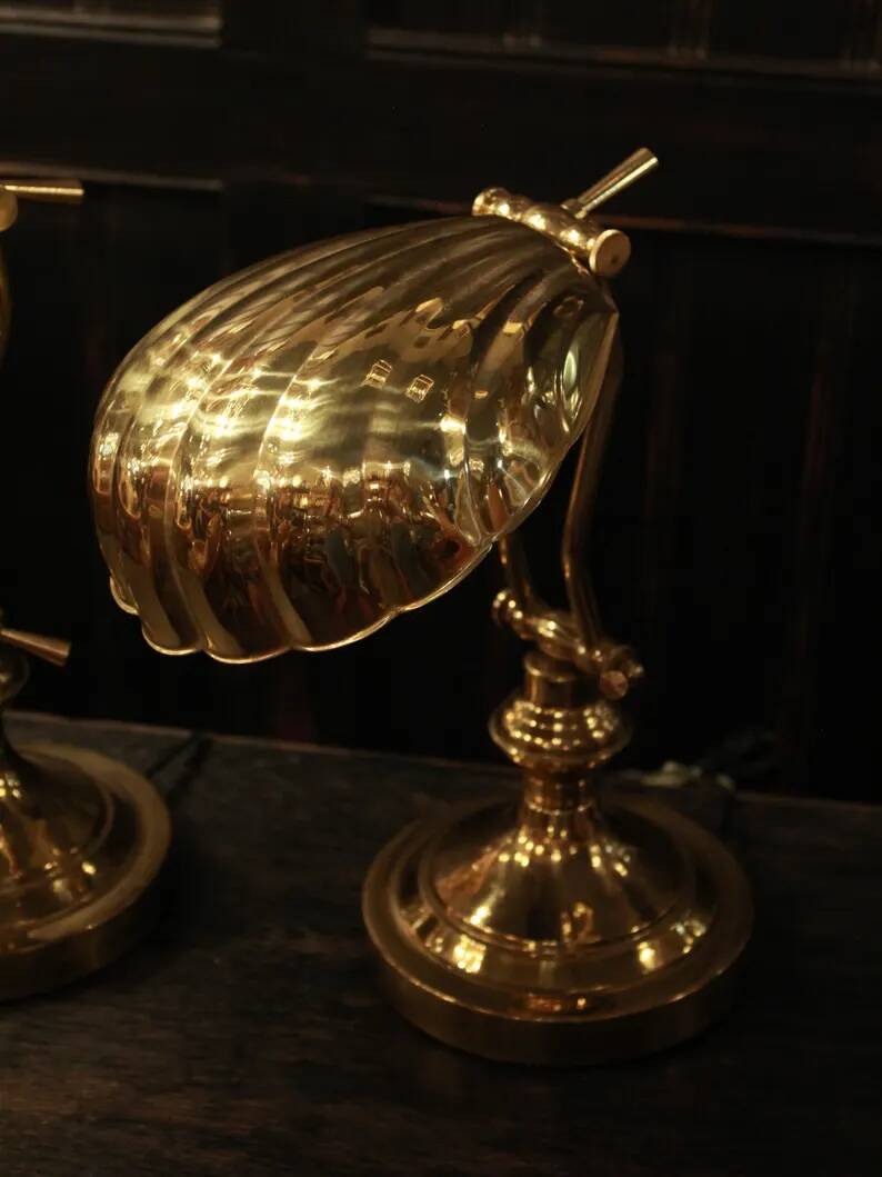 Pair of articulated brass lamps in the shape of a shell.