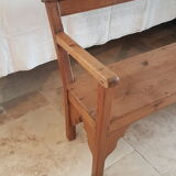 Church bench in fir tree with armrests