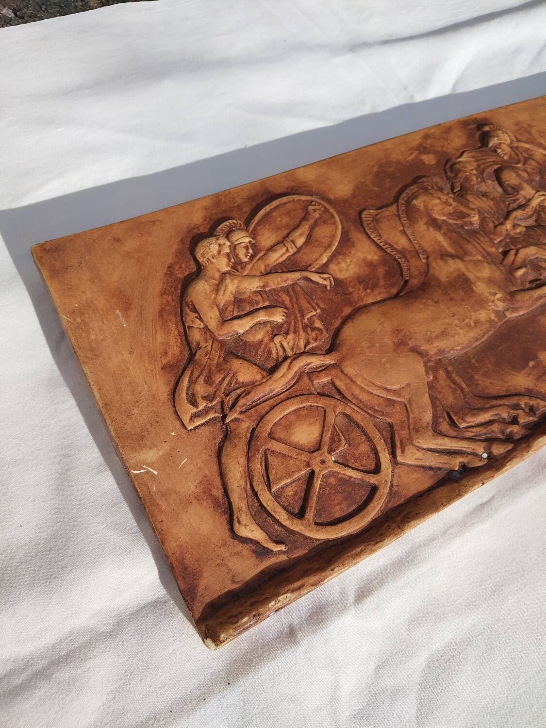 Bas-relief plaster scene of horses and a cart.