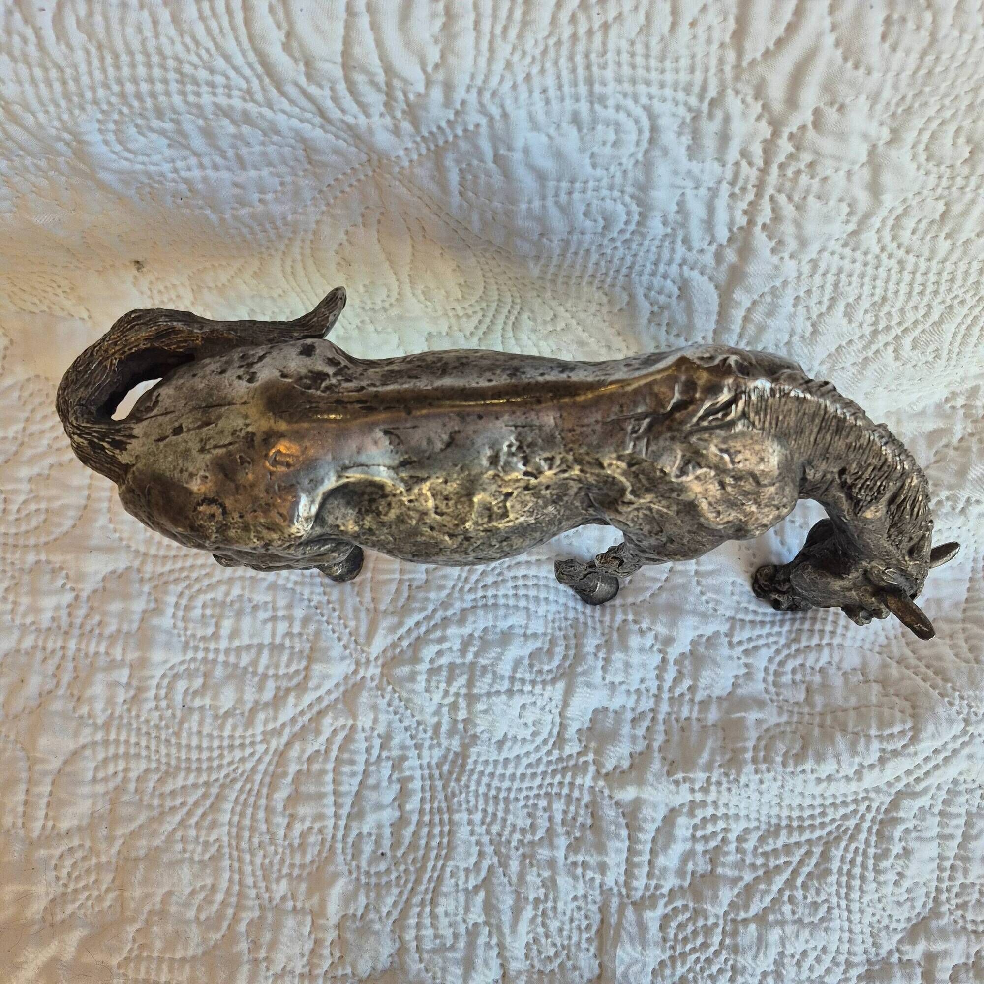 Sculpture of a grazing horse with a silver finish.