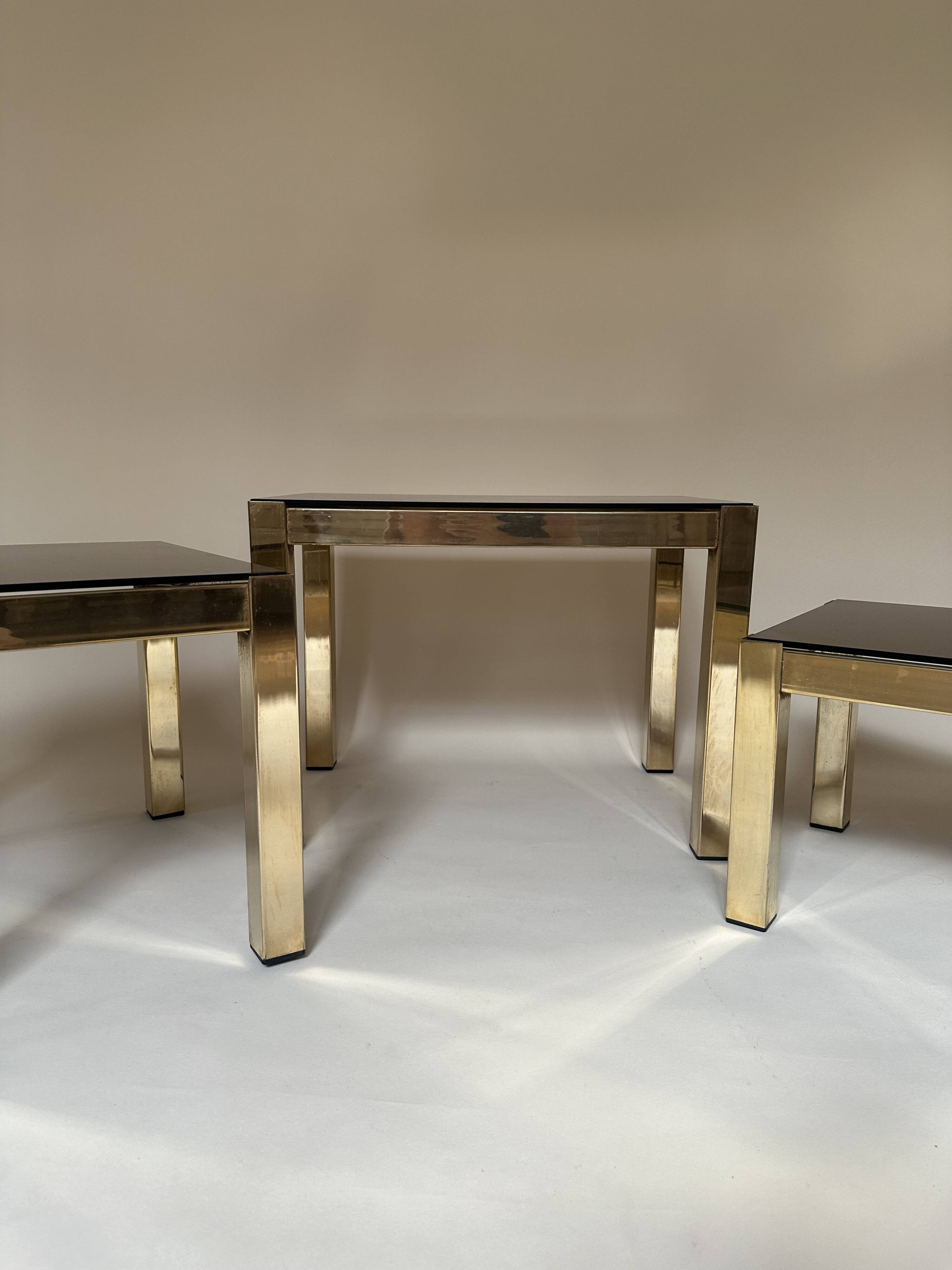 Set of three nesting side tables in brass and smoked mirror.