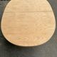 Renovated oval Scandinavian extendable dining table in wood with a central leg.
