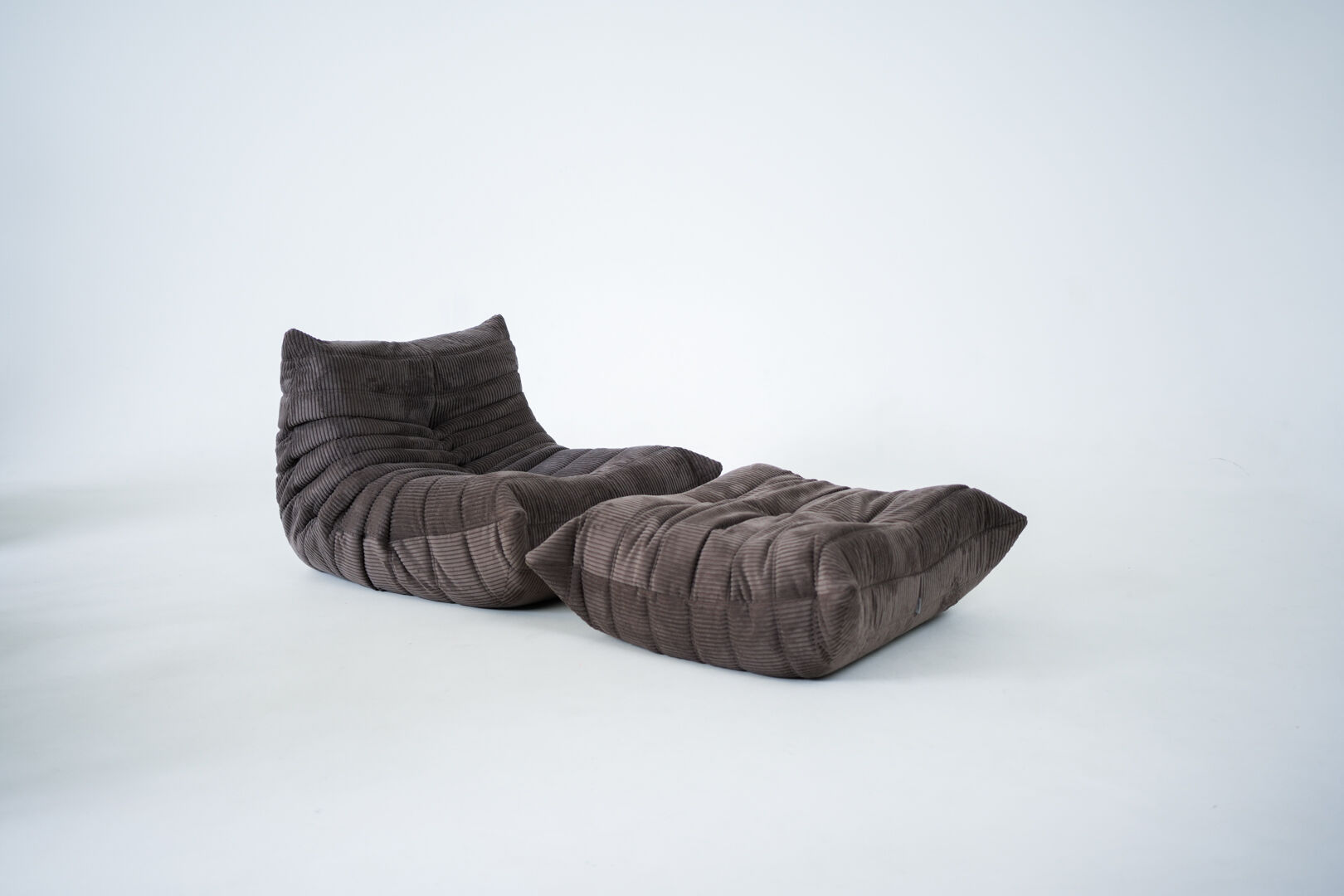 Ensemble de chaise et pouf Togo en velours côtelé marron.