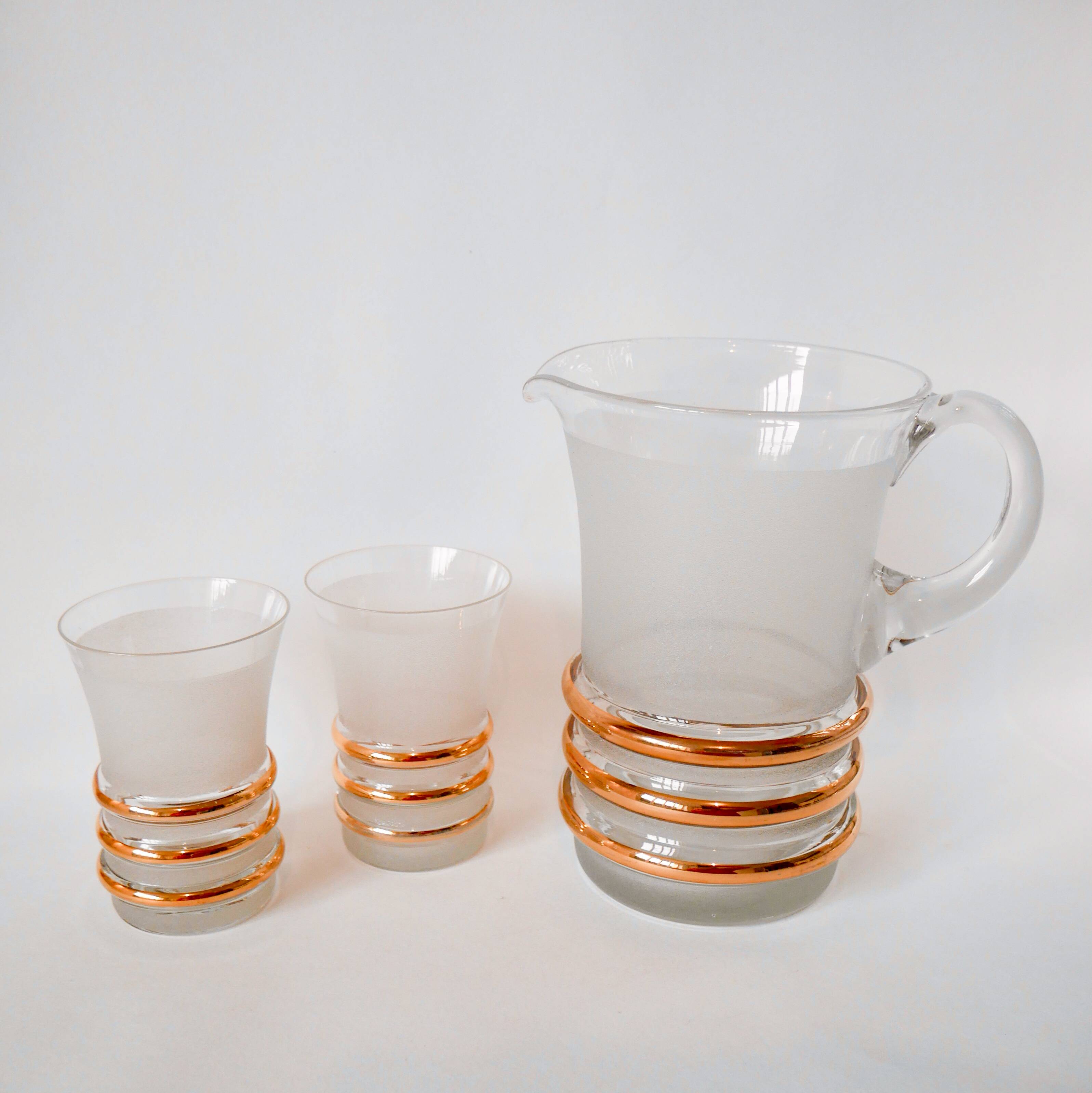 set composed of a pitcher and two large white granite glasses with gold edging from the 60s