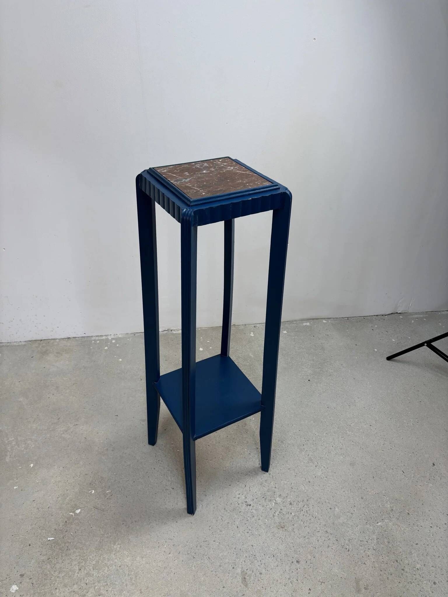 Blue side table with a veined stone top and a low shelf in the Art Deco style.