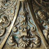 Baroque/Antique style torch candleholder, nineteenth, gilded bronze. Head motifs, volute arabesques