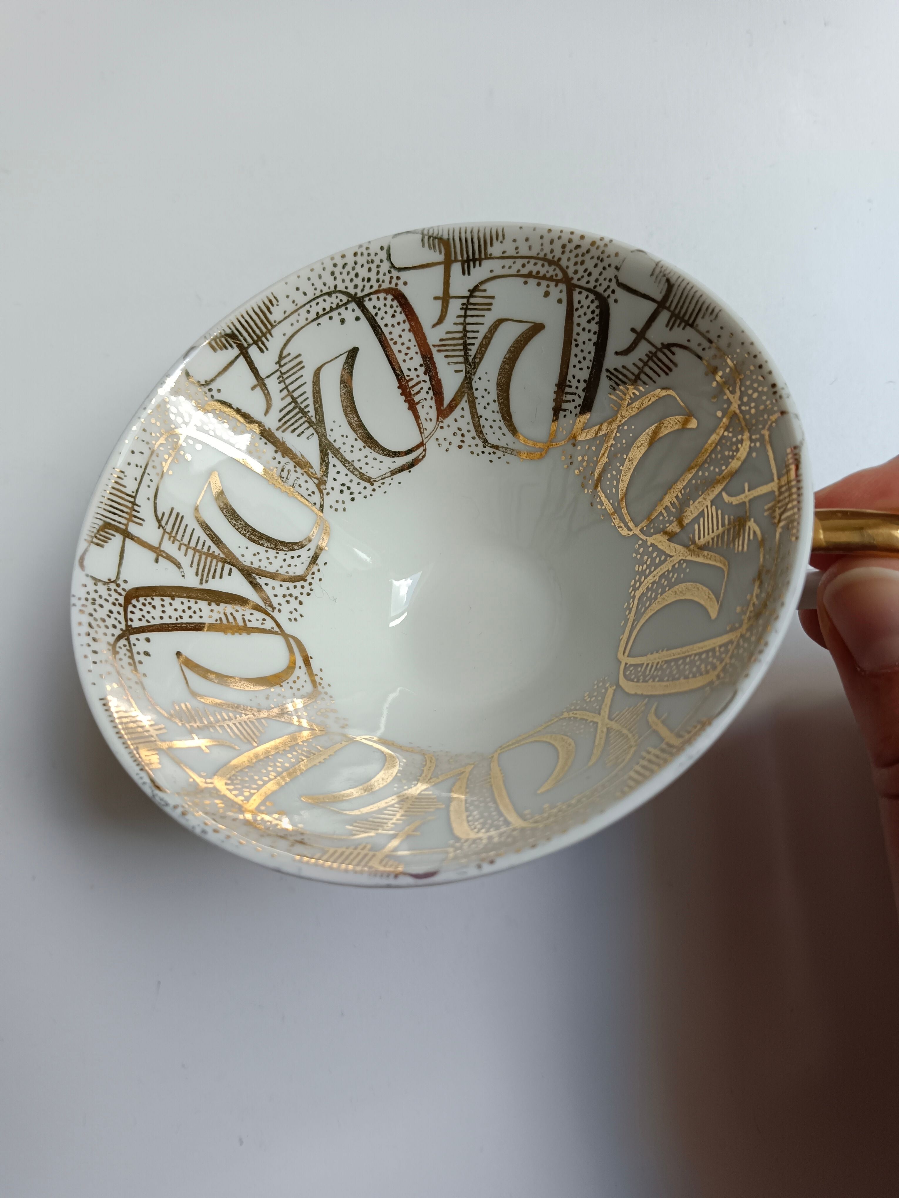 Solitaire tea cup, saucer, and dessert plate in white and gold.