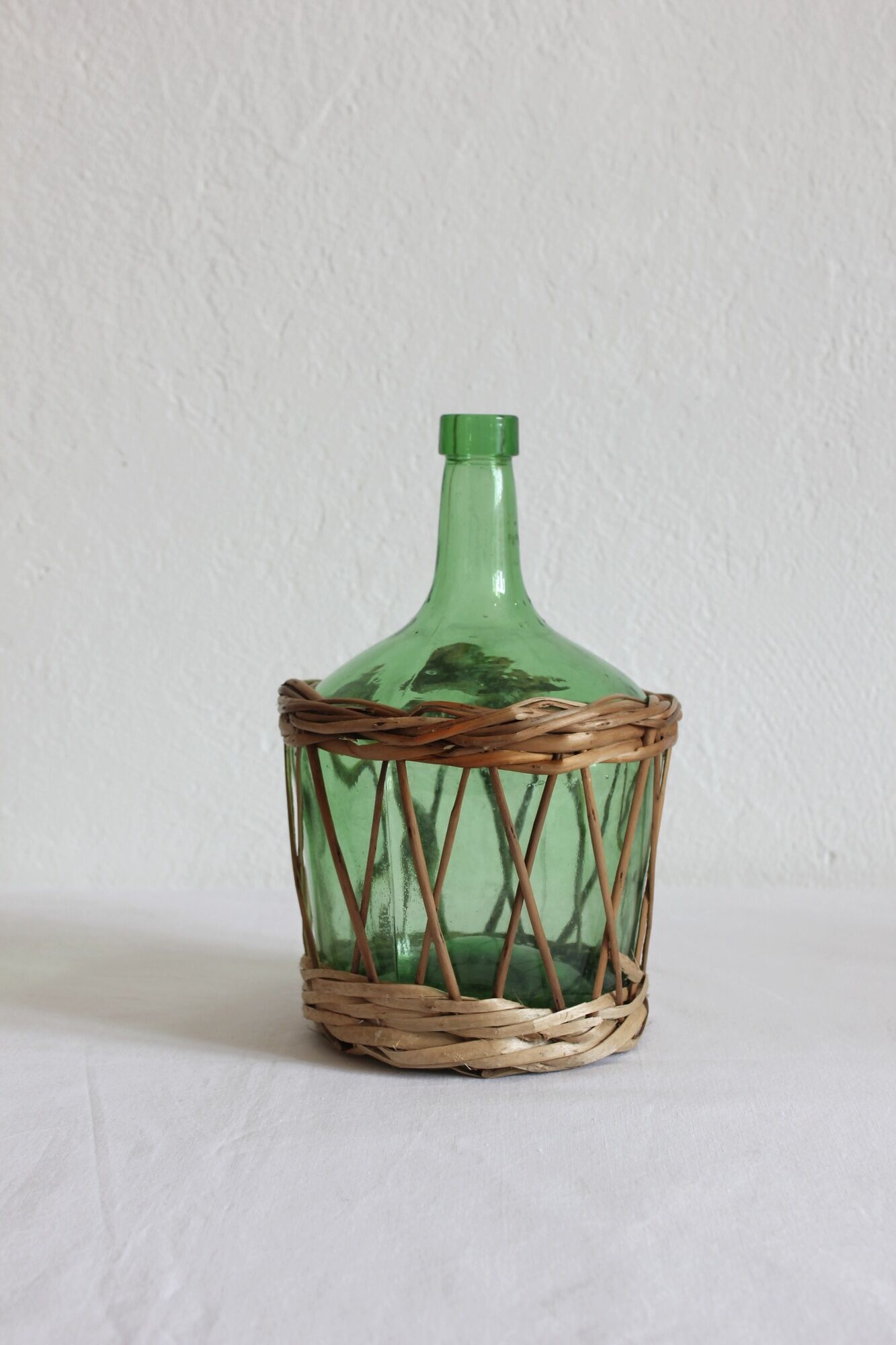 Dame jeanne verte vintage entourée de rotin / osier