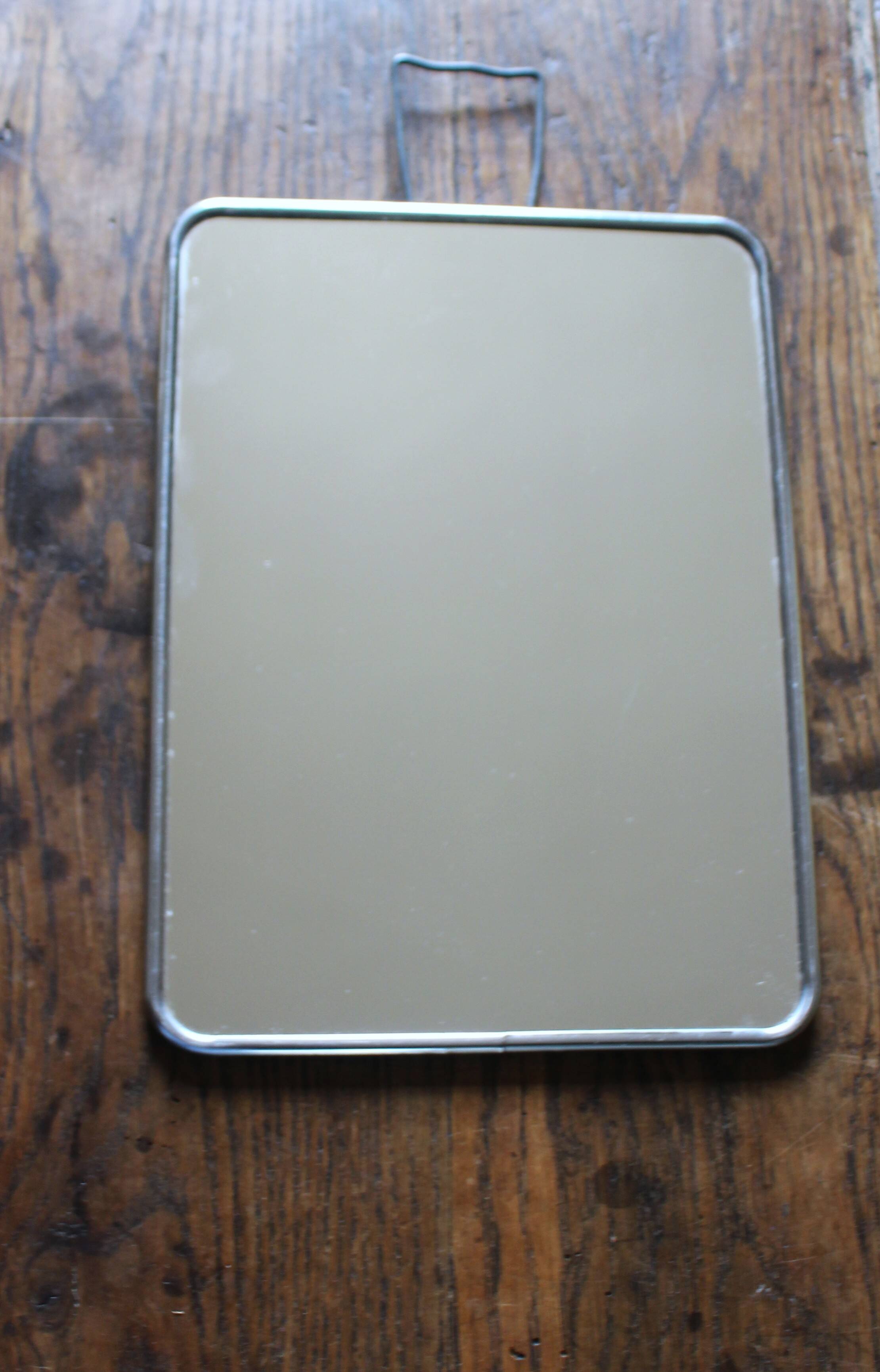 Simple rectangular barber mirror with a stand.