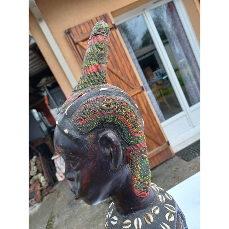 African statue of a woman, made of wood, brass, beads, and seashells.