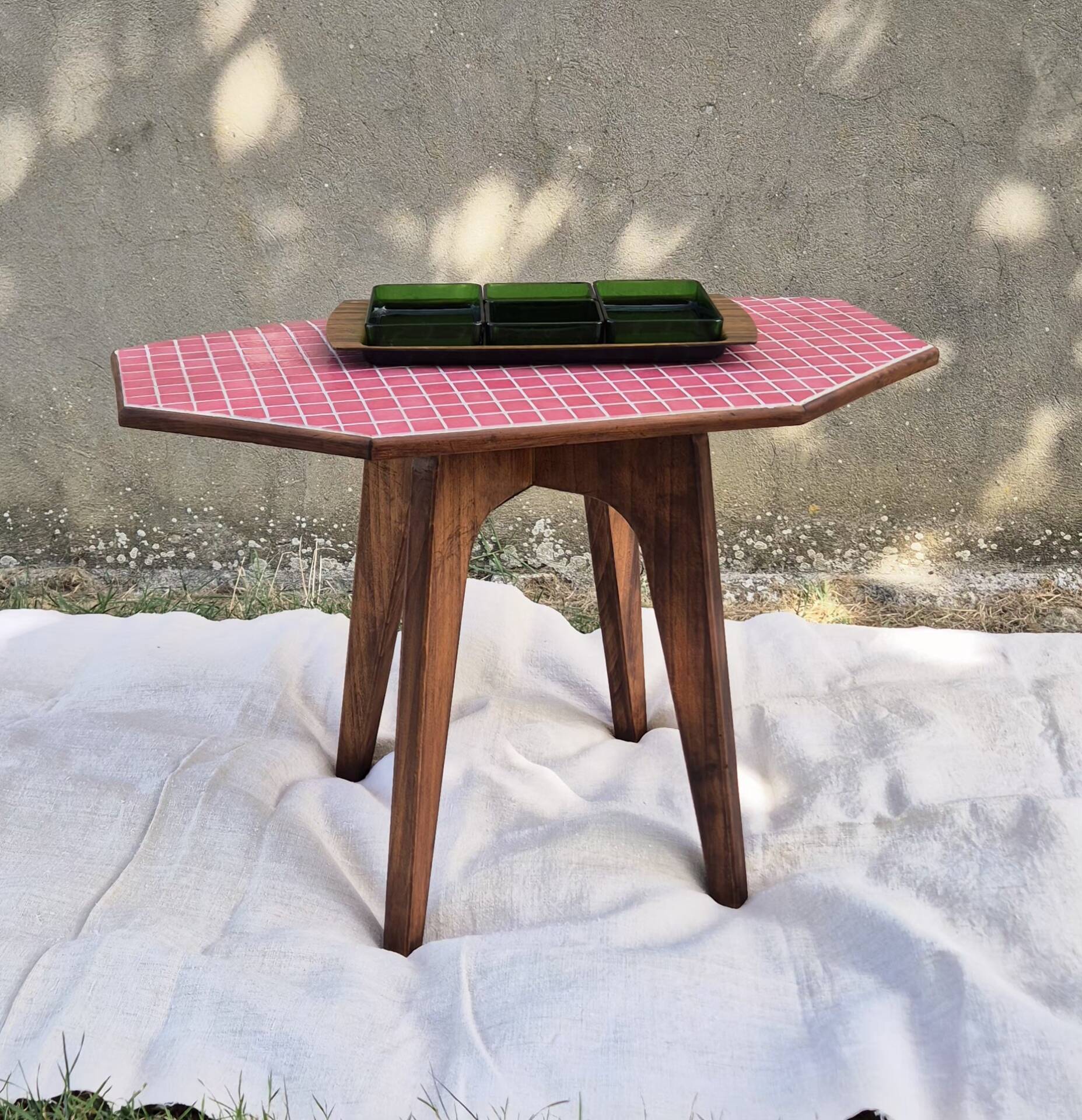 Small Scandinavian side table with wood and pink tiles, with tapered legs.