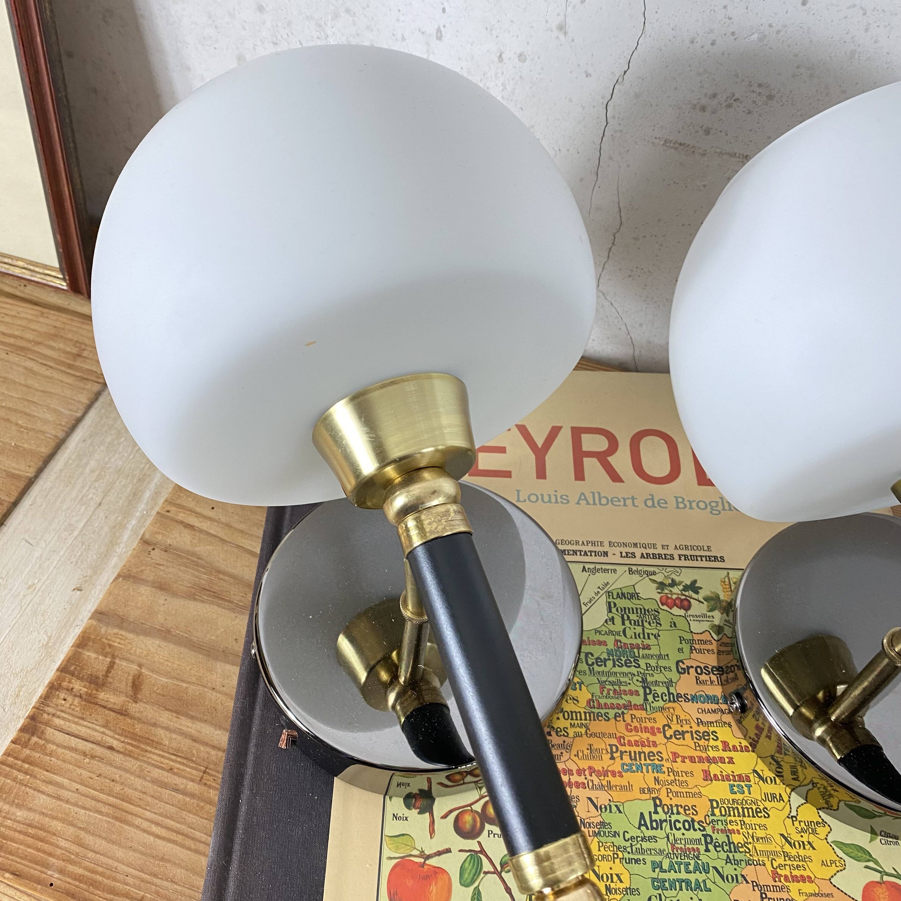 Pair of wall sconces with brass torch and white glass globe.