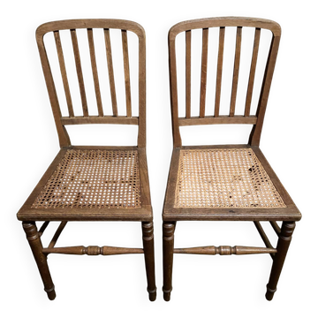 Set of 2 antique wooden chairs with caned seats.