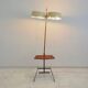 Brass and lacquered metal floor lamp with a wooden magazine shelf.