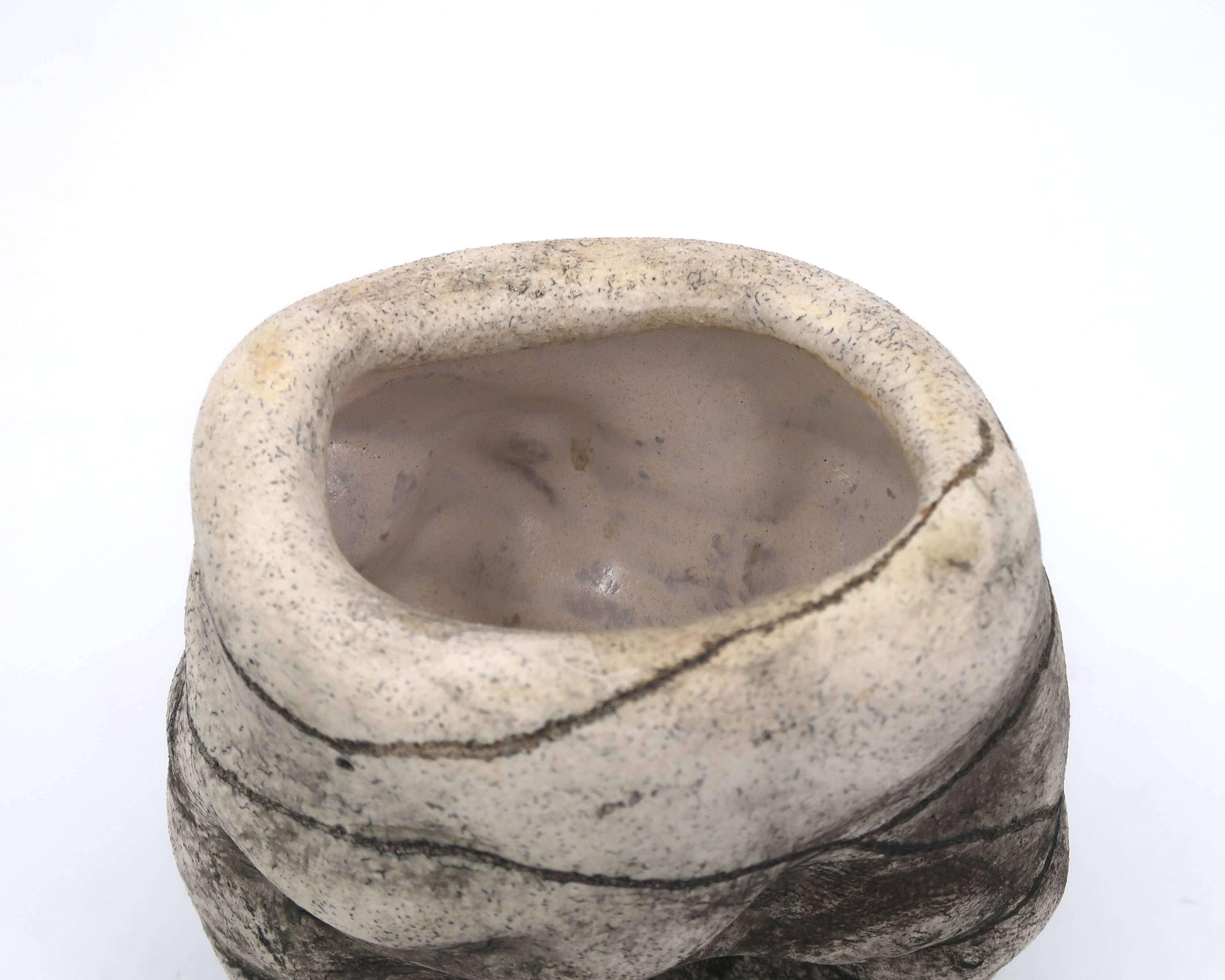 Ceramic vase sculpture decorated with faces and featuring a hole, 1980s.