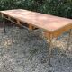 Table vintage moderniste à piétement tubulaire métallique et plateau recouvert d’une toile cirée.